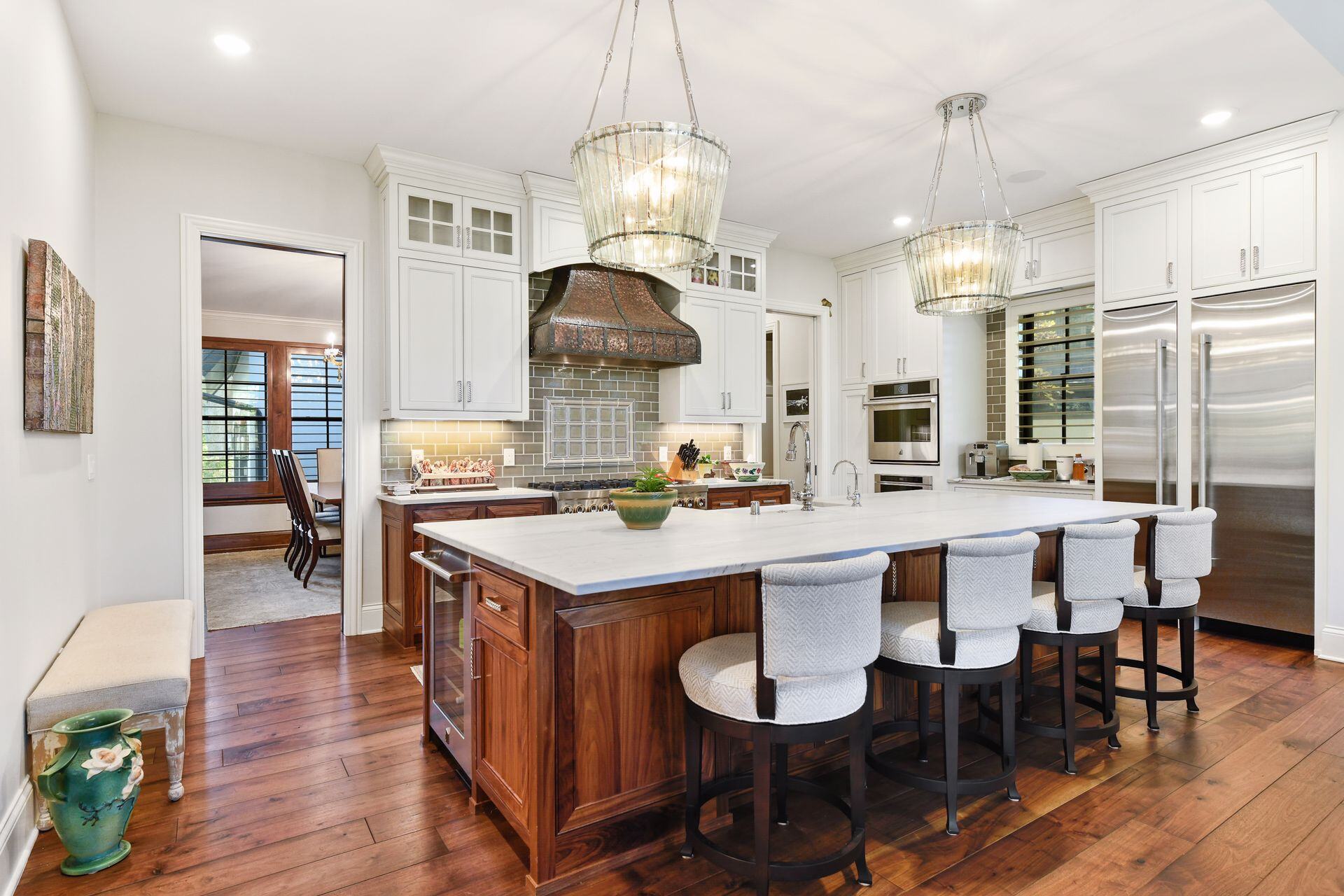 Remodeled kitchen featuring rich wood, statement chandeliers, and tile backsplash by Executive Remodeling in Minneapolis, MN